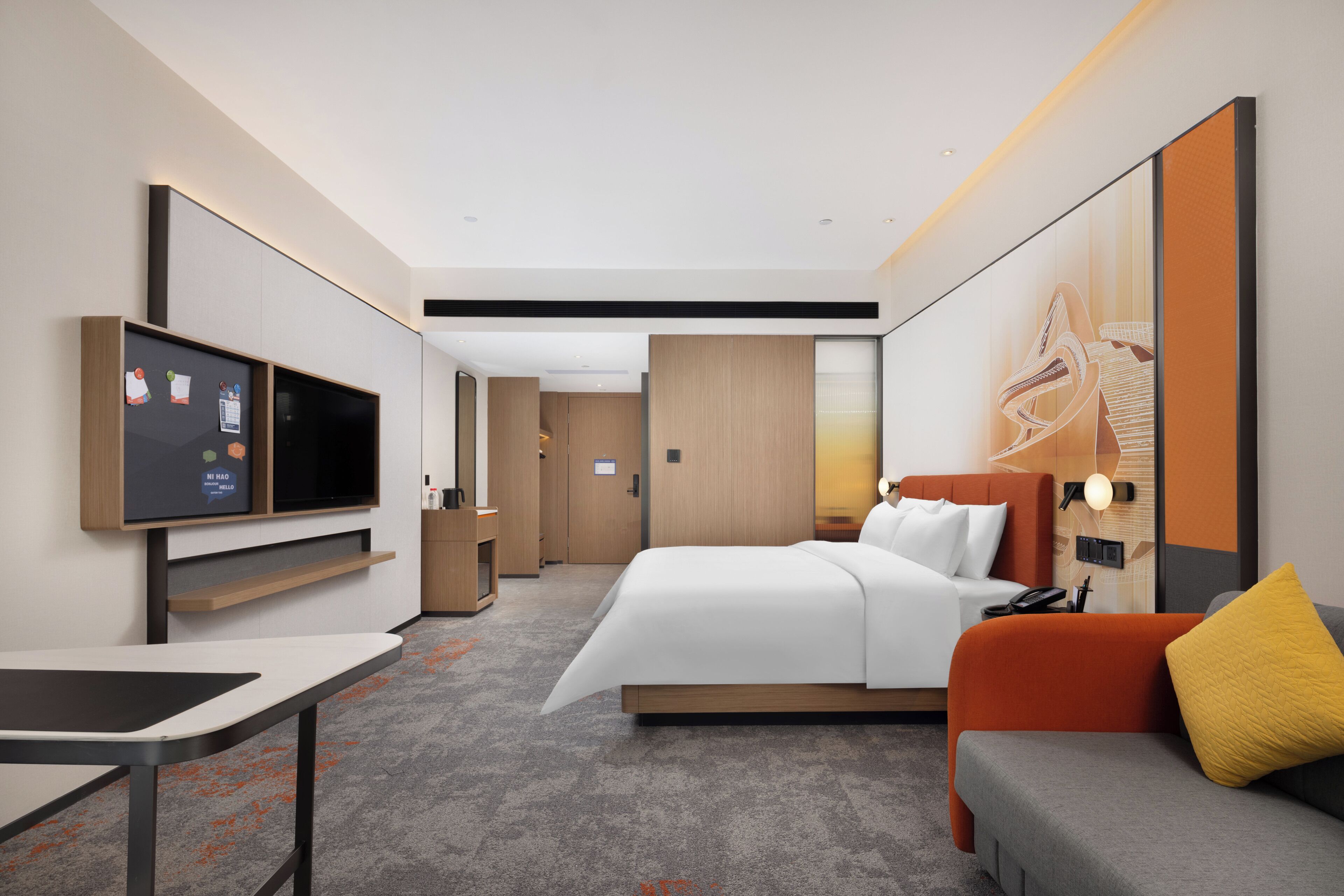 Una habitación de hotel moderna con cama, sofá, televisor, escritorio y una obra de arte grande en la pared.