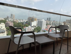 A balcony with two chairs, a table, and a city view.