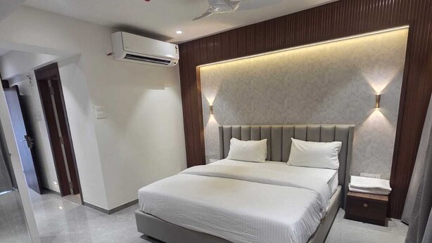 Un dormitorio moderno con una cama grande, ventilador de techo, iluminación empotrada y un equipo de aire acondicionado.