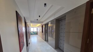 Un pasillo con piso de mármol, varias puertas y una obra de arte en la pared.