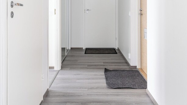 A hallway with a wooden floor, white walls, and a door at the end. - Luxurious Penthouse - Hot Tub & Sauna (Tampere)