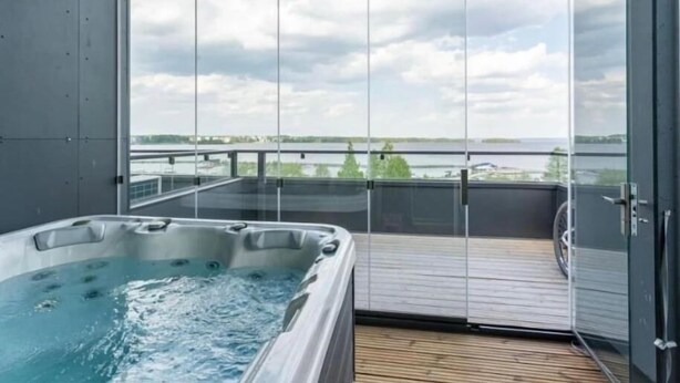 Ein Whirlpool auf einem Balkon mit Blick auf ein Gewässer und einen bewölkten Himmel.