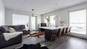 Ein moderner Wohnraum mit Sofa, Essbereich und großem Fenster mit Blick auf die Stadt.