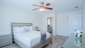 A bedroom with a bed, nightstands, a dresser, a ceiling fan, and a door. - Southern Pines Hideaway – Peaceful Hahira Stay (Hahira)