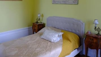 A bedroom with a bed, two bedside tables, a nightstand, a patterned rug, and two wall-mounted lamps.