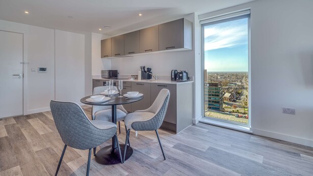 A modern kitchen with a dining area, large window, and city view.