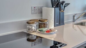 A kitchen counter with jars, a plate of food, and a paper towel holder.