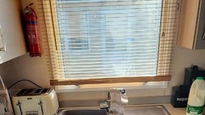 A small kitchenette with a toaster, sink, and window blinds. - Weymouth Bay Holiday Park - Holiday Accommodation 15694 (Weymouth)
