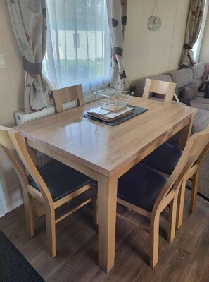 Ein Holztisch mit Stühlen, ein Korb und ein Willkommensschild an der Wand.