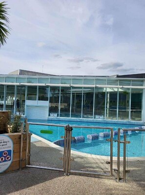 Une piscine entourée d’une paroi en verre, délimitée par une clôture en bois, et sur laquelle est apposé un panneau indiquant qu’il est interdit de plonger.