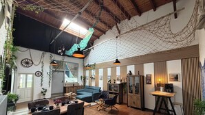 A cozy, well-lit room with a wooden floor, a blue sofa, a dining table with chairs, and a coffee machine. - Wohnglück Alte Werft Leer (Leer (Ostfriesland))