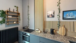 A modern kitchen with a built-in oven, a sink, and a countertop with a cutting board and a knife. - Wohnglück Alte Werft Leer (Leer (Ostfriesland))