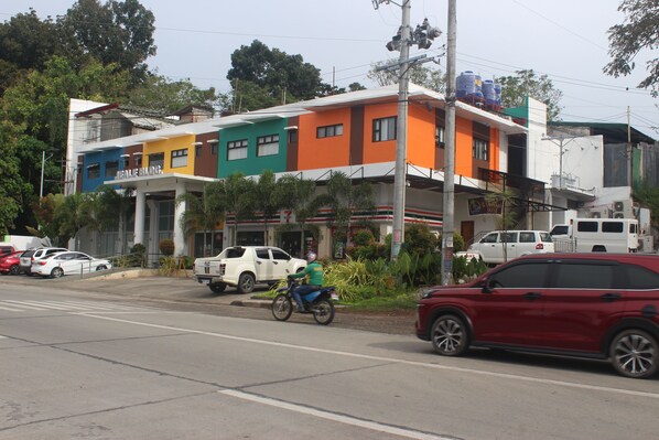 A multi-story building with a colorful facade, a visible commercial sign, and a parked vehicle in front. - Balay ni Jose (Tagbilaran)