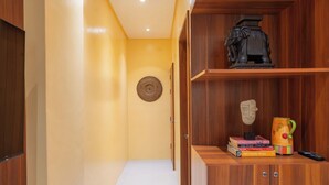 A hallway with wooden cabinets, a woven wall hanging, and a shelf with books and a decorative mug. - Balay ni Jose (Tagbilaran)