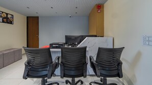 A modern office space with three black office chairs, a desk with a computer, and a marble accent wall. - HOTEL MONVILLE ALKAPURI (Vadodara)