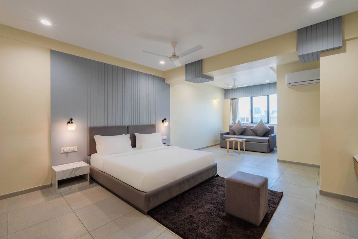 A modern bedroom with a large bed, a sofa, and a ceiling fan.