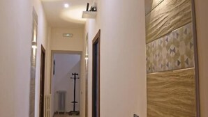 Un corridoio stretto con pavimento in legno, faretti a incasso nel soffitto e una parete decorata con un motivo a mosaico geometrico.