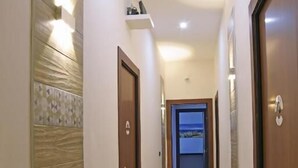 Un corridoio con pavimento in legno, una parete con motivo geometrico e una porta in fondo.