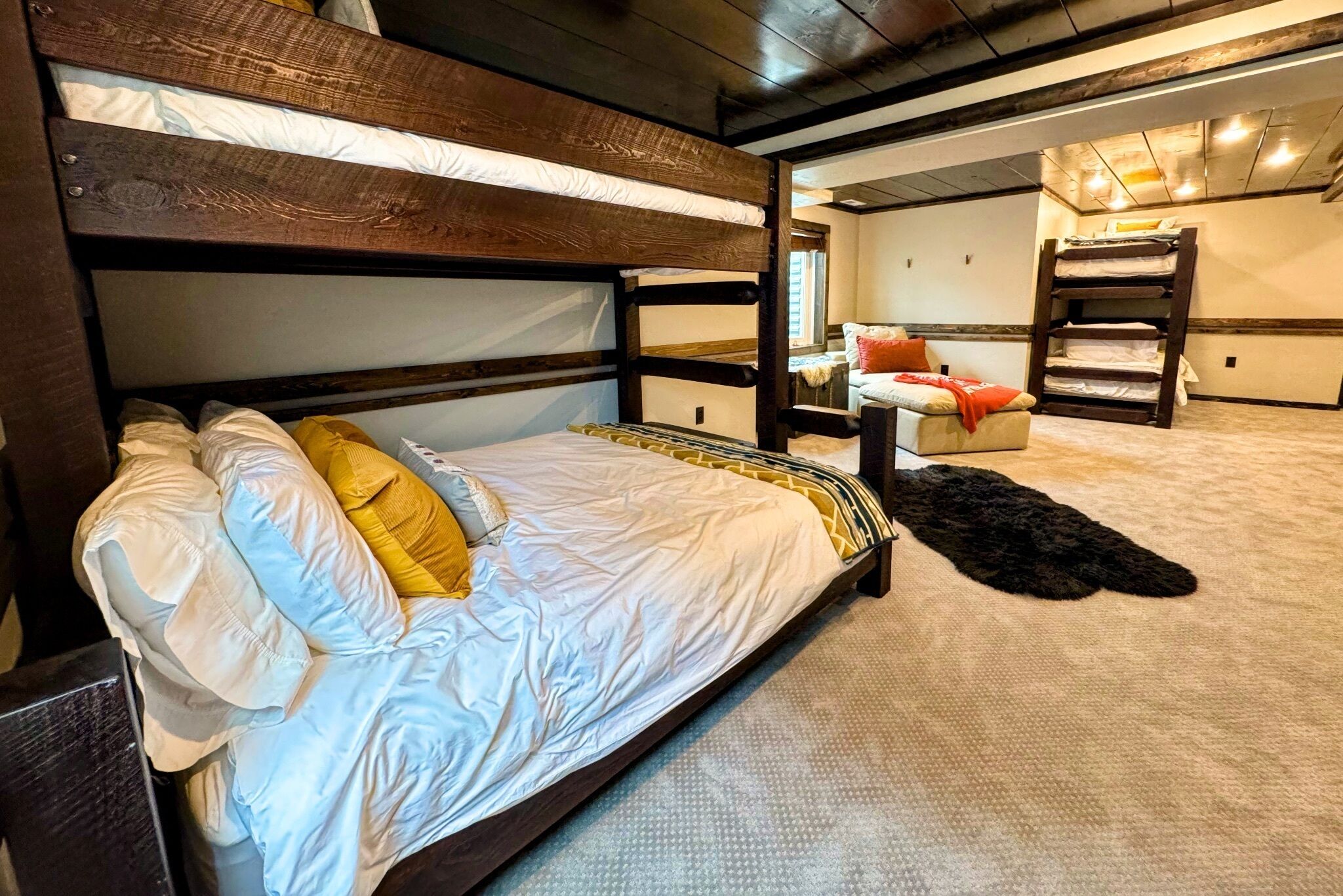 A bunk bed with a headboard, a small table with a chair, and a black furry rug on the floor.