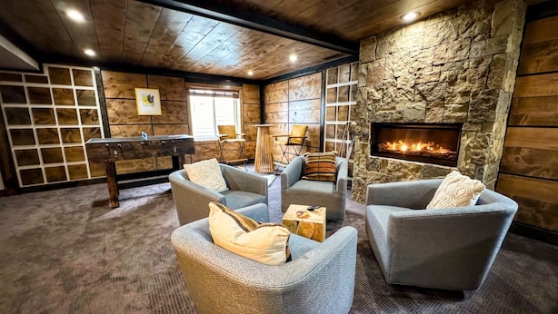 A cozy lounge area with stone walls, a fireplace, and comfortable seating.