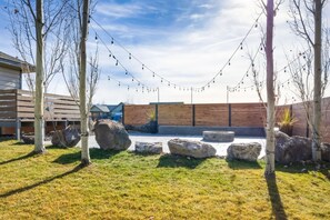 Een binnenplaats met een houten terras, grote rotsen en lichtslingers.