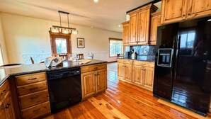 A kitchen with wooden cabinets, a black refrigerator, and a dishwasher.