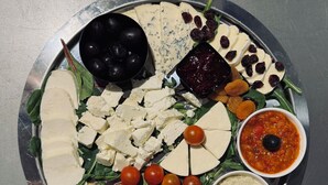 A platter with various cheeses, olives, tomatoes, and dips. - Chateau D'Amour Luxury Boutique (Bucharest)