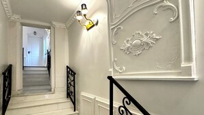 A staircase with white walls, a black railing, and a wall-mounted light fixture. - Chateau D'Amour Luxury Boutique (Bucharest)