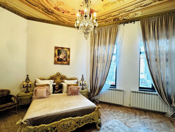Un dormitorio con una cama grande, techo decorado y ventana con cortinas.