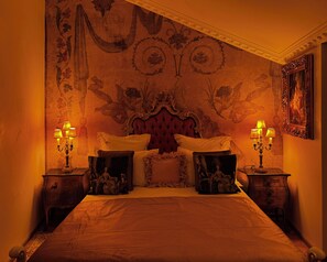 A bedroom with a large bed, ornate headboard, and decorative wall panels. - Chateau D'Amour Luxury Boutique (Bucharest)