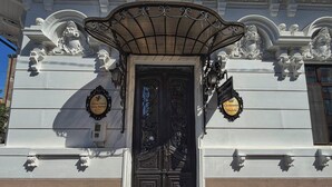A building facade with a black ornate door, a decorative awning, and two signs indicating 'Chateau d'Ymau' and 'Corona Hotels.' - Chateau D'Amour Luxury Boutique (Bucharest)