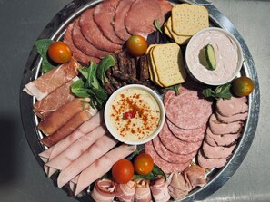 Eine Platte mit verschiedenen Fleischsorten, Käse und einer Dipsoße.