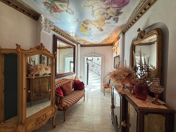 Un vaste hall d’entrée orné de miroirs décoratifs, agrémenté d’un canapé moelleux et d’un escalier menant à l’étage supérieur.