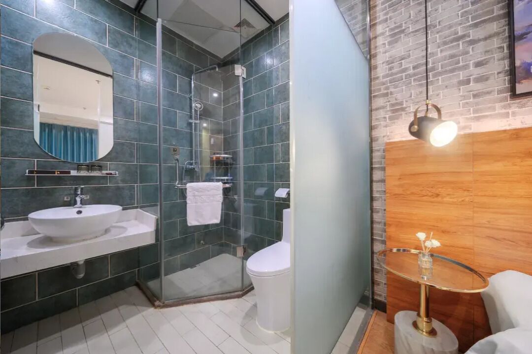 A modern bathroom with a glass shower enclosure, a white sink, and a toilet.