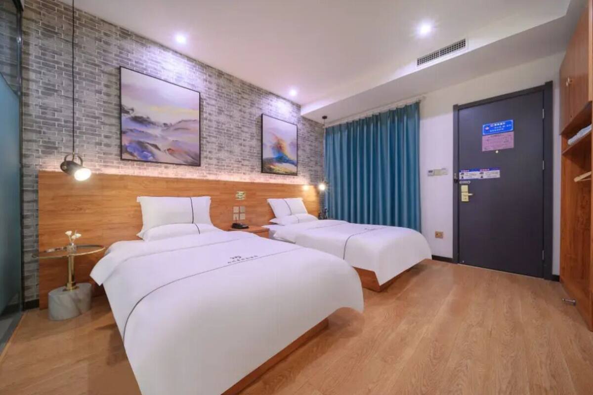 A hotel room with two beds, a brick wall, and a door with a sign.