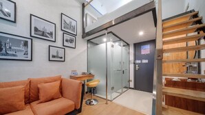 A modern interior with a sofa, framed pictures, a glass door, and a staircase. - Qiqiaowu Hotel Songjiazhuang Station (Beijing)