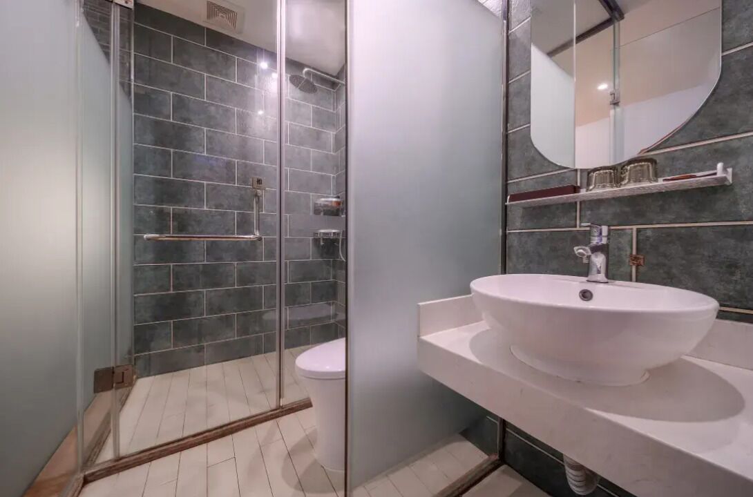 Ein modernes Badezimmer mit Duschkabine aus Glas, einem weißen Waschbecken und einem Spiegel.