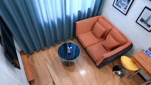 A room with a sofa, a round table, a chair, and a curtain. - Qiqiaowu Hotel Songjiazhuang Station (Beijing)