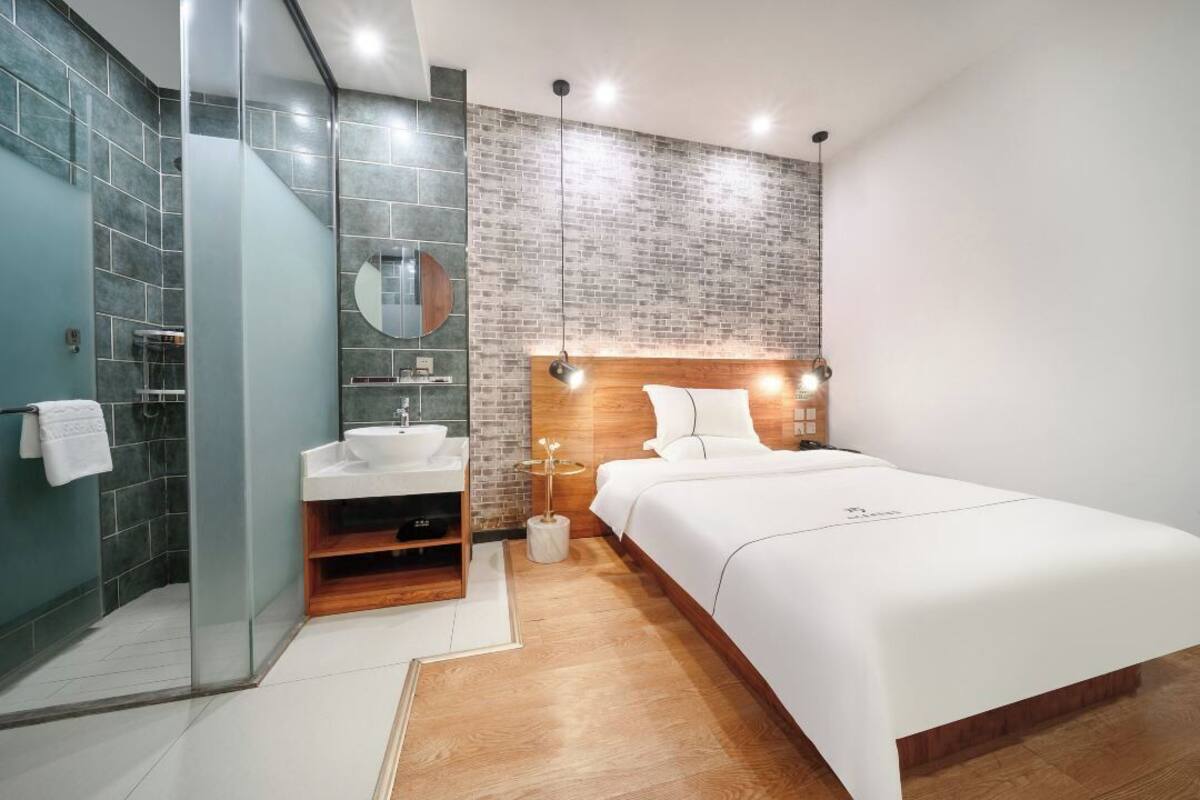 A modern bedroom with a bed, bedside table, and a mirror.