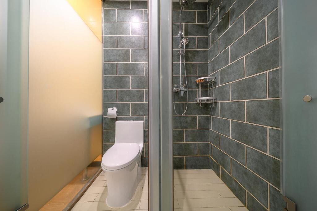 A bathroom with a toilet, a shower with a glass door, and tiled walls.