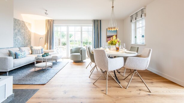 A modern living room with a sofa, coffee table, and dining area with chairs and a table. - Sjipwai-Hüs 13c - Sjipwai-Hüs 13c in Westerland (Sylt)