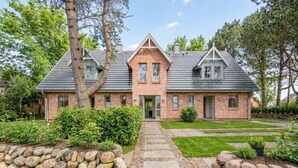 A brick house with a stone pathway leading to the entrance, surrounded by greenery and trees. - Sjipwai-Hüs 13c - Sjipwai-Hüs 13c in Westerland (Sylt)