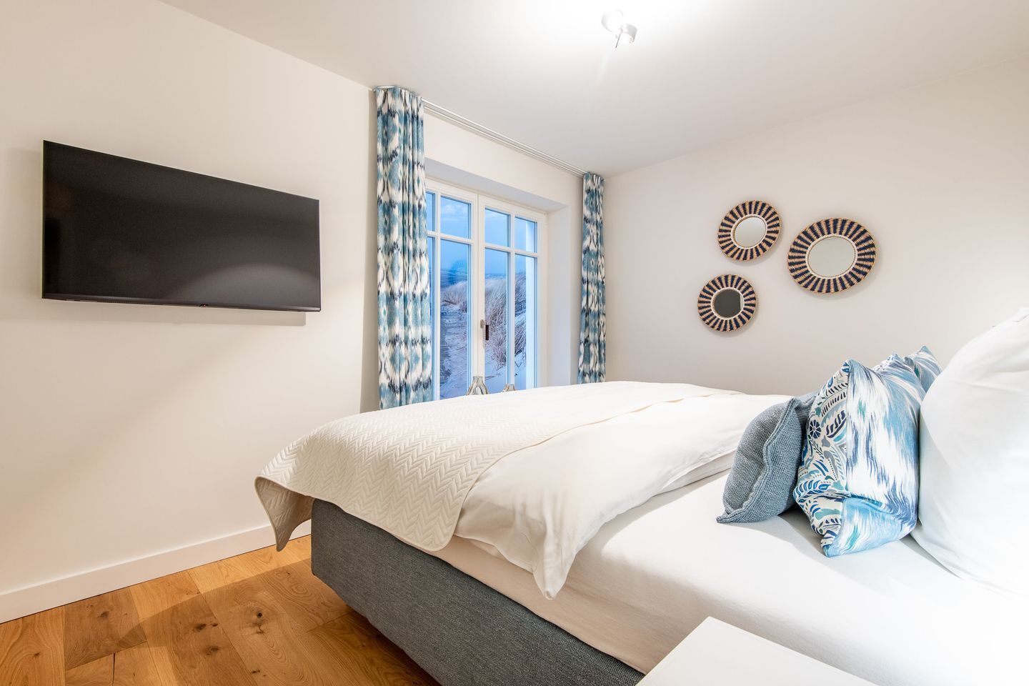 A bedroom with a bed, a TV, a window with curtains, and wall decor.