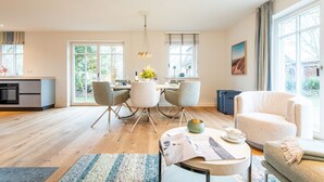 Un salon moderne comprenant un coin repas, une cuisine et de grandes fenêtres.