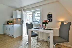 A modern kitchen with white cabinets, a dining table with two chairs, and a window with a view of the outside.