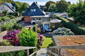 A residential property with a sloped roof, a fenced garden, and a patio area with outdoor furniture.