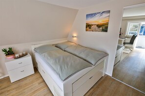 A bedroom with a bed, bedside table, and a painting on the wall.