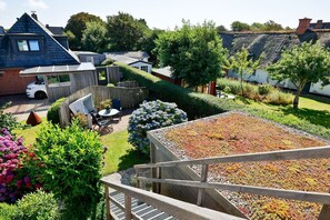 A residential garden with a patio, a car, and a thatched-roof house.
