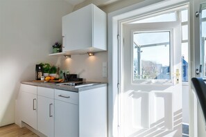 A modern kitchen with white cabinets, a countertop, and a window with a view of the outside.