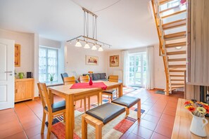 Ein Essbereich mit Holztisch, Stühlen, einer roten Tischmatte und einer hängenden Leuchte.